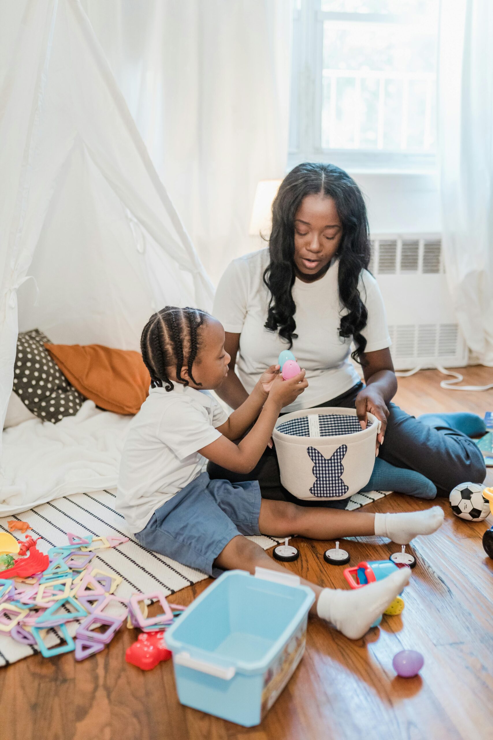 African American mother and son playing with toys indoors, enjoying quality family time.